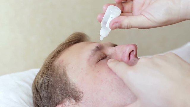 Man dripping medicine in the eye