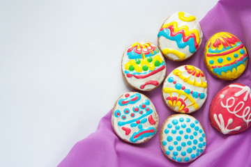 Festive cookies in the form of Easter eggs with purple napkin on a white background