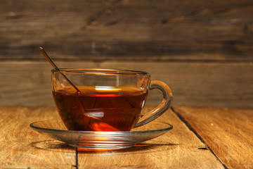 Tea in a glass cup with a kettle on a wooden table. Close-up.
