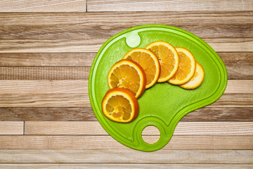 Sliced orange slices on a cutting board that lies on a wooden background of oak parquet
