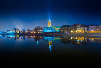 Fototapeta na wymiar Panoramic view of famous old island Tumski with cathedral of St. John reflection in the Odra river at dusk. Wroclaw, Poland, EU. A long time shutter exposure.