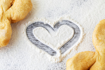 heart of flour on the table along with pastries from dough