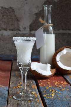 Coconut liqueur in glass with broken coco. Delicious Pinacolada milk cocktail with rum. Alcohol drink liquor. Glass bottle and shot. Copy space
