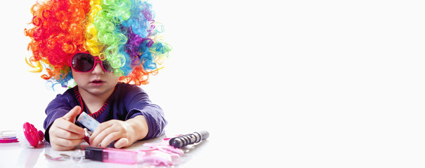 Cute little child girl with colorful hair having fun and doing makeup. Humorous image. Happy childhood, beauty, joy concept.