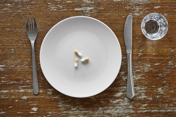 three pills on plate knife and fork nutrition supplements