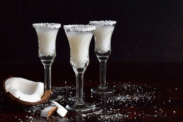 Coconut liqueur in glass with broken coco. Delicious Pinacolada milk cocktail with rum. Alcohol drink liquor. Copy space