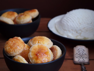 Cheese cookies in black bowls, vintage spoon and fresh cheese in background