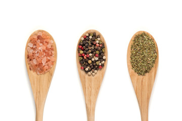 Various spices on wooden spoons isolated on white background. (pink salt,  pepper, oregano)
