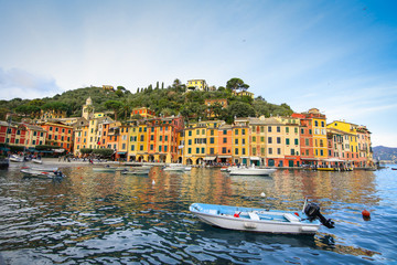 Naklejka premium Colorful buildings on the promenade of Portofino with boats floating in the marina and blue sky background