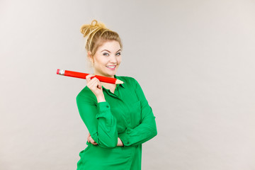 Smiling woman holds big pencil in hand