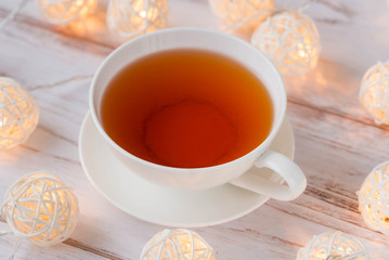 Cup of black tea and Christmas garlands glow