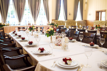 Beautiful table setting with crockery and flowers for a party, wedding reception or other festive event. Glassware and cutlery for catered event dinner.
