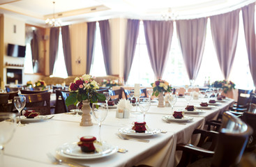 Beautiful table setting with crockery and flowers for a party, wedding reception or other festive event. Glassware and cutlery for catered event dinner.
