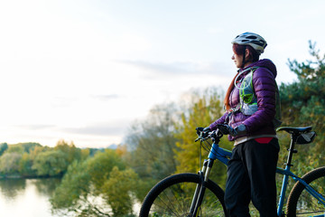 Image of girl with bicycle in helmet in autumn