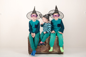 Happy children in elegant green clothes are playing at home. Boys in carnival glasses and a hat are posing for a fashion magazine