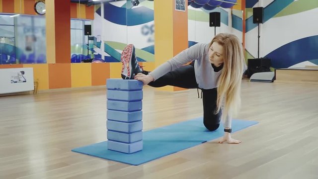Blonde pretty young woman doing splits in the gym.