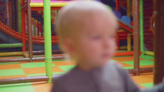 blond toddler runs olding two balls and then plays with toy car