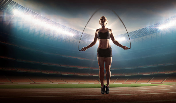 fit woman exercising with jumping rope on a stadium