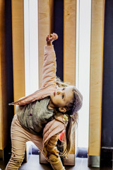 Little child in a pink suit poses near the wall