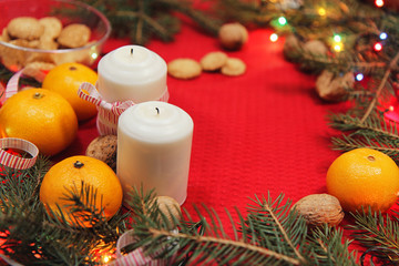 Christmas tree toys on a red napkin. Mandarins and candles on th