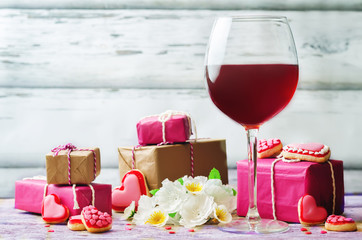 Glass of red wine with heart shape cookies, flowers and gifts
