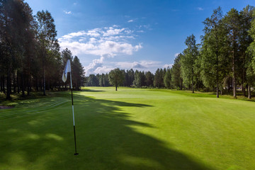 Obraz premium Landscape of golf field with hole flag on foreground