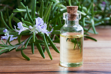 A bottle of rosemary essential oil with fresh blooming rosemary twigs