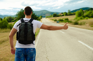 Fototapeta premium A passenger with a backpack stands on the road and stops
