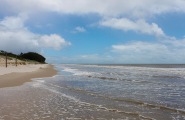 Almost deserted beach with waves lapping the shore at high tide