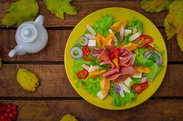 Autumn salad of jamon, lettuce, tomatoes, cheese. Wooden rustic background. Selective focus. Top view