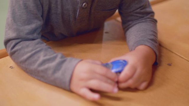 Close up of toddler's hands playing with toycar on table