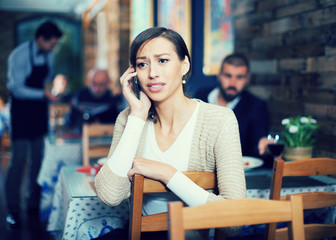  upset female holding mobile in the restaurant