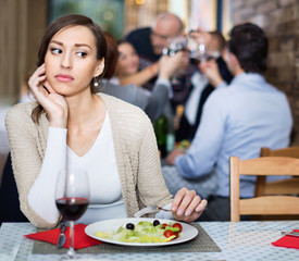 Portrait of upset woman in the restaurant with salad and wine