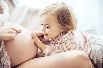 Fototapete Rund Charmante Tochter, die den Bauch einer schwangeren Mutter berührt © konradbak
