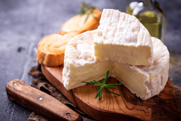 Camembert cheese with rosemary on wooden board - obrazy, fototapety, plakaty