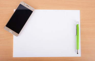 White blank paper sheet with a pen and a smartphone on a wooden table