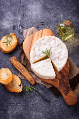 Camembert cheese with rosemary on wooden board