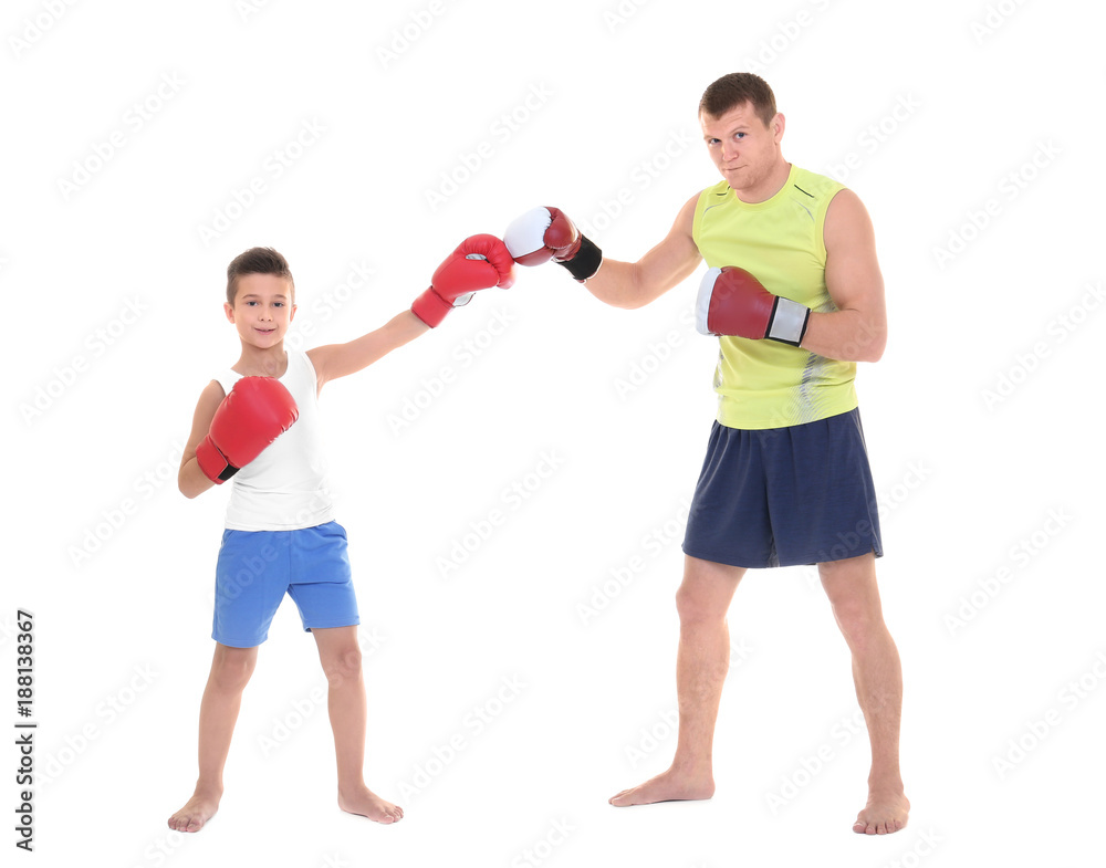 Wall mural Cute little boy training with boxing coach, on white background