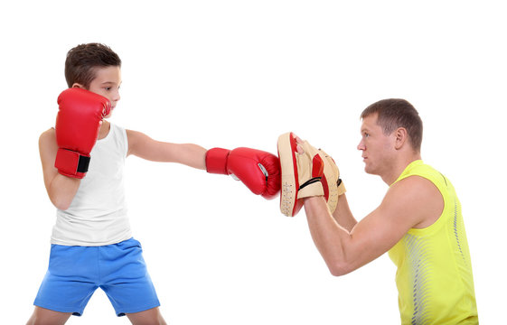 Cute little boy training with boxing coach, on white background