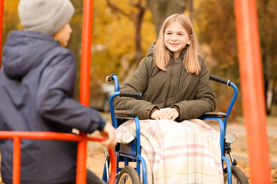 Little girl in wheelchair and boy on playground