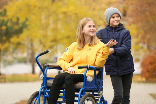 Little girl in wheelchair with brother outdoors