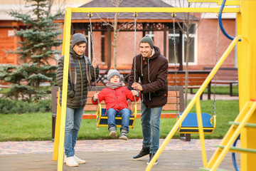 Male gay couple with adopted boy at playground