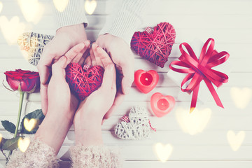 Valentine's Day. Young couple hands holding gift box over white wooden background. Love concept. Top view