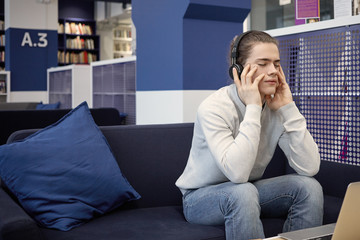 People, relaxation, leisure and entertainment concept. Casually dressed young man practicing meditation, listening to music using headphones, closing eyes, having calm and peaceful expression