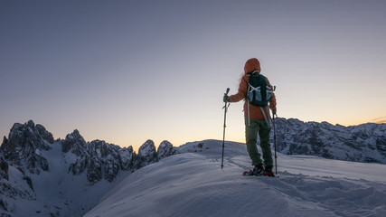Inspiring background of young woman exploring the top of the snow capped mountain