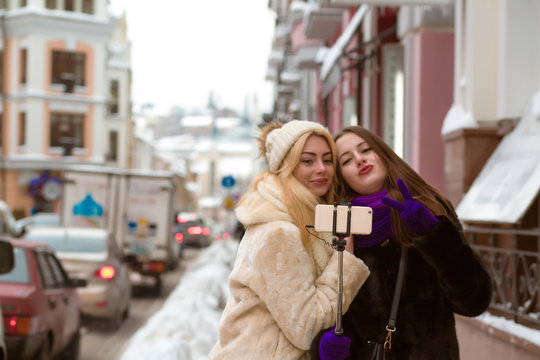 Outdoor portrait of emotional pretty women friends making self portrait at street in winter