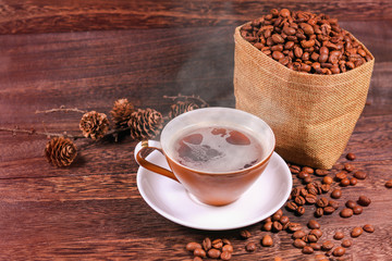  Cup of black coffee and coffee beans in a bag on wooden background with copy space .