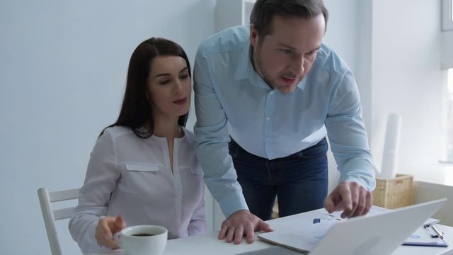 Cannot hide the feelings. Millennial woman listening to her office coworker and embracing his arm while flirting with him.