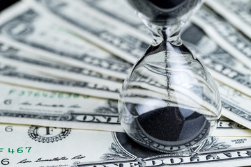 Sandglass or hourglass on US dollar banknotes using as time for investment or financial deadline countdown concept