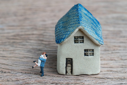 Miniature Couple, Happiness Husband And Wife With Ceramic House Using As Success Marriage Life Or Mortgage Concept